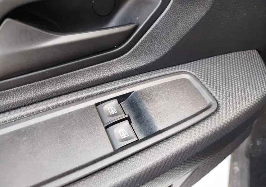 Gros plan sur les commandes électriques des vitres côté conducteur d'une Dacia Sandero 2025, intérieur noir texturé.