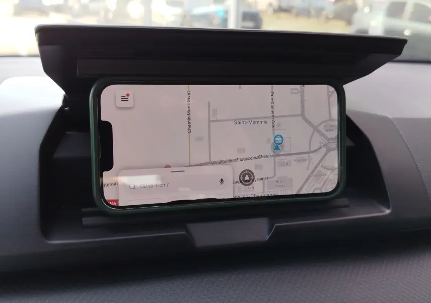 Vue intérieure du tableau de bord d'une Dacia Sandero 2025 avec smartphone affichant une carte GPS intégrée.