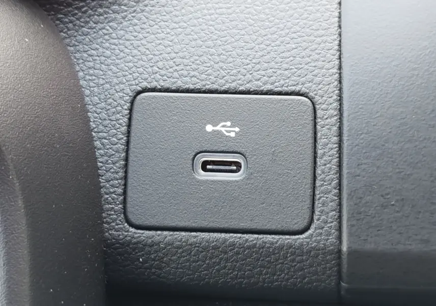 Gros plan sur un port USB-C intégré dans le tableau de bord noir d'une Dacia Sandero Blanc Glacier 2025.