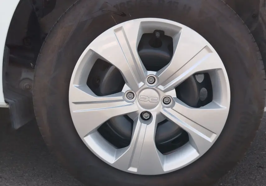 Gros plan sur la roue avant gauche de la Dacia Sandero blanche, mettant en valeur la jante en alliage argentée au design moderne.