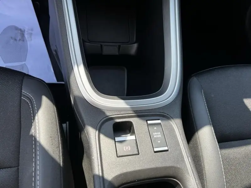 Vue rapprochée de la console centrale noire du Jeep Avenger blanc 2025, avec boutons de frein à main électronique et mode de conduite.
