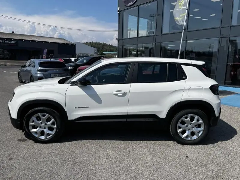 Vue de profil côté gauche d'un Jeep Avenger blanc électrique 2025 avec jantes argentées et détails noirs contrastants.