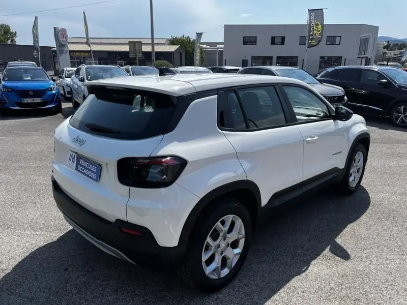 Jeep Avenger électrique blanc en 3/4 arrière droit, avec toit noir contrastant et feux arrière fumés.