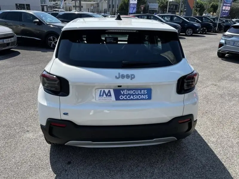 Vue arrière d'un Jeep Avenger blanc électrique 2025 avec logo Jeep et plaque "Véhicules Occasions" visible.