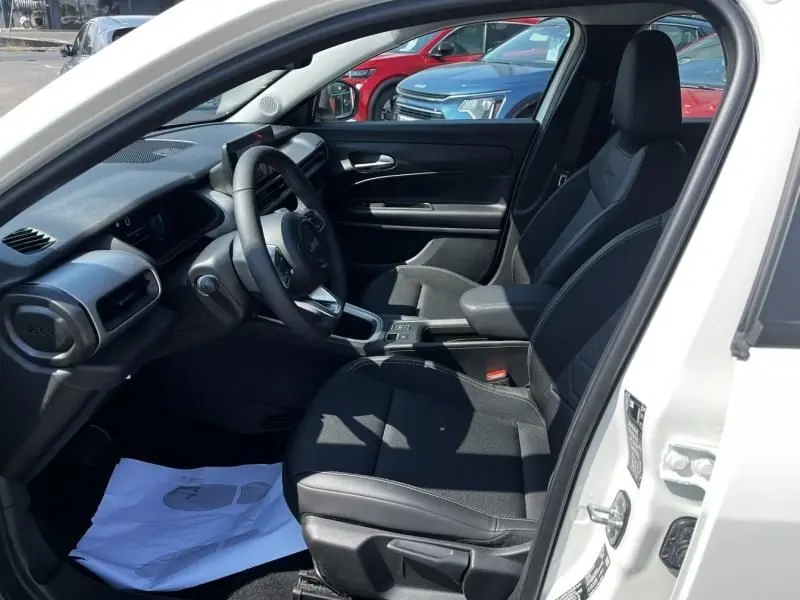 Vue intérieure côté conducteur du Jeep Avenger blanc 2025, mettant en valeur les sièges noirs et le tableau de bord moderne.