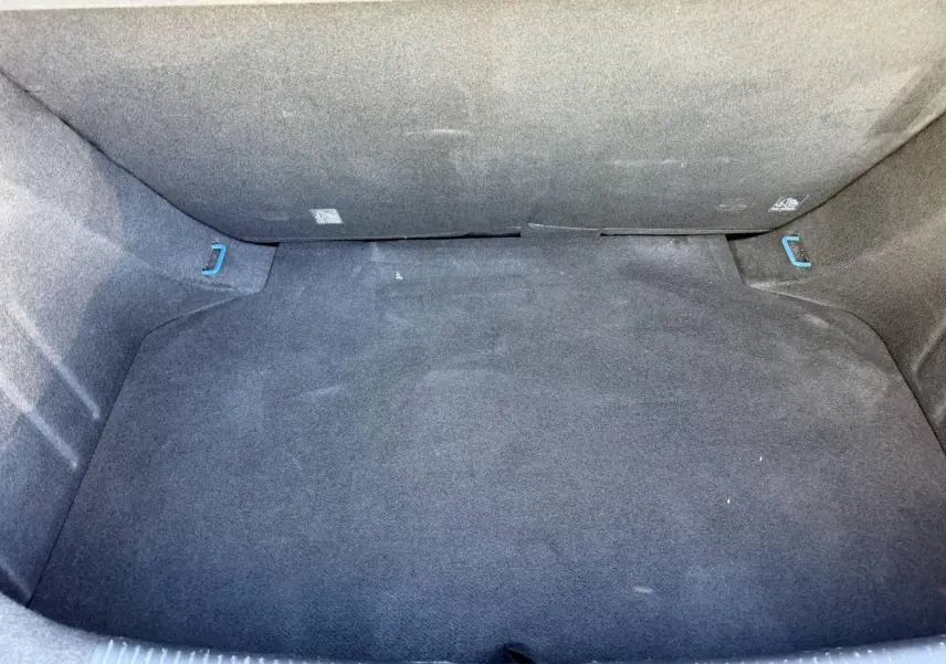 Coffre vide vu de dessus, revêtement noir avec crochets bleus visibles dans un MG3 Como Blue métallisé 2025.