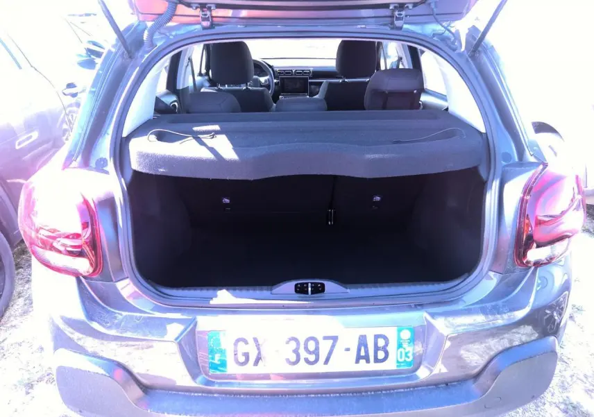 Vue arrière ouverte sur le coffre d'une Citroën C3 gris foncé 2024, avec banquette arrière et intérieur visibles.