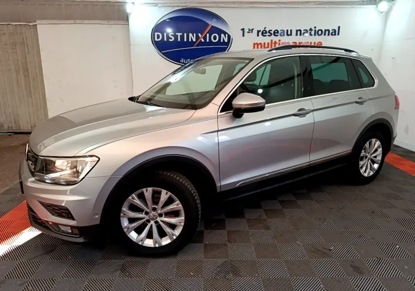 Volkswagen Tiguan gris clair vu de profil côté gauche dans un showroom avec logo Distinxion en arrière-plan