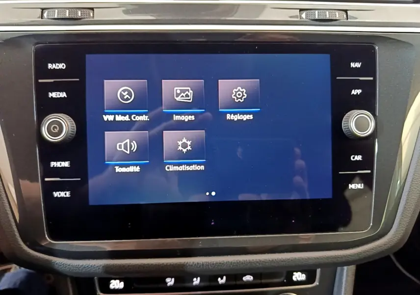Écran tactile central du tableau de bord du Volkswagen Tiguan gris clair, affichant les réglages multimédias et climatisation.