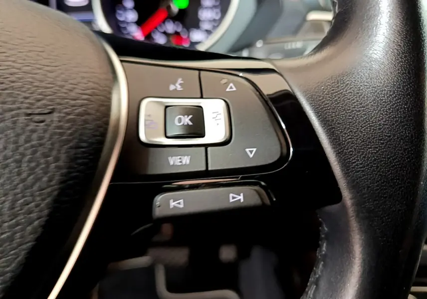 Gros plan sur les commandes gauche du volant cuir noir du Volkswagen Tiguan 2020, boutons multifonctions visibles.