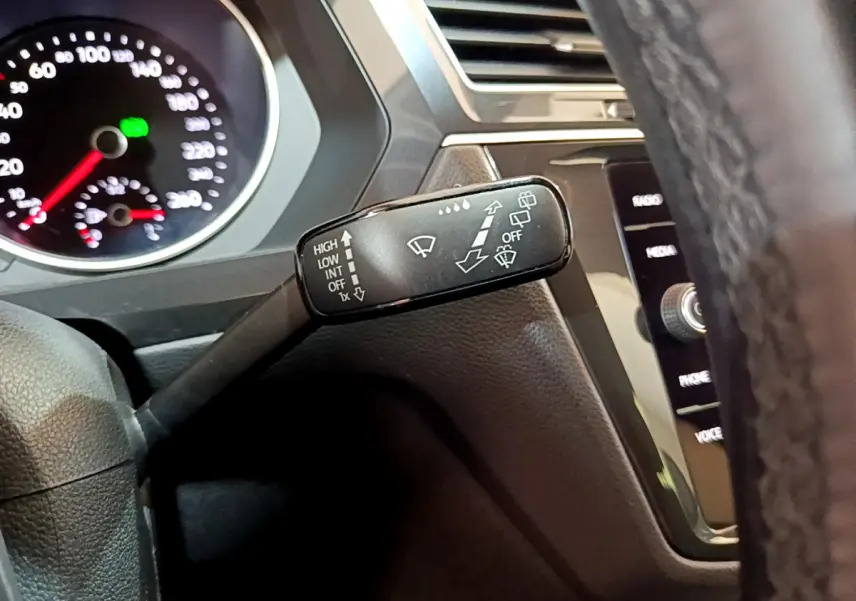 Gros plan sur la manette d’essuie-glace du Volkswagen Tiguan 2020, tableau de bord et volant en cuir visibles.