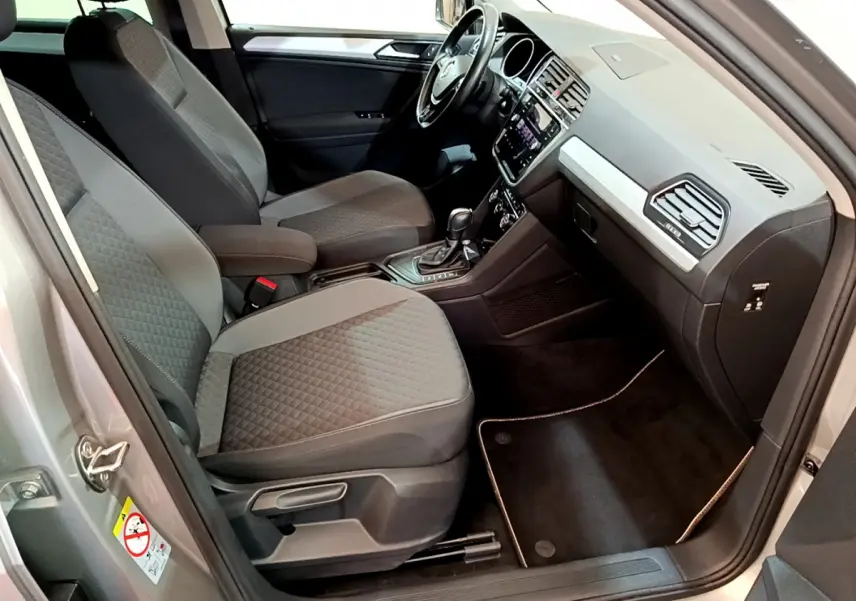 Intérieur avant droit du Volkswagen Tiguan gris clair 2020, sièges tissu gris et tableau de bord avec écran tactile.