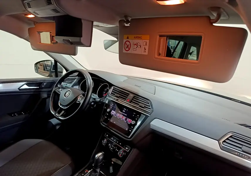 Intérieur du Volkswagen Tiguan 2020 vu côté conducteur, volant cuir, écran tactile et pare-soleil ouvert avec miroir.