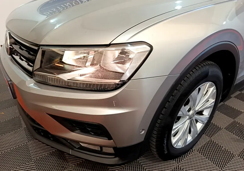 Vue 3/4 avant droit d'un Volkswagen Tiguan gris clair mettant en valeur le phare LED et la jante alliage.