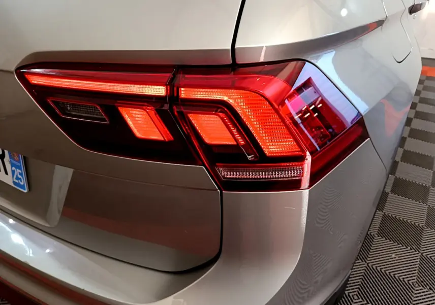 Gros plan sur le feu arrière droit rouge d'un Volkswagen Tiguan gris clair 2020, avec la trappe à carburant visible.