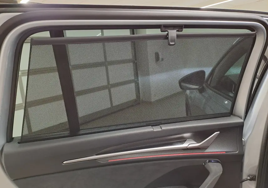 Vue intérieure sur la porte arrière droite du Skoda Kodiaq gris argent avec pare-soleil en filet déployé.