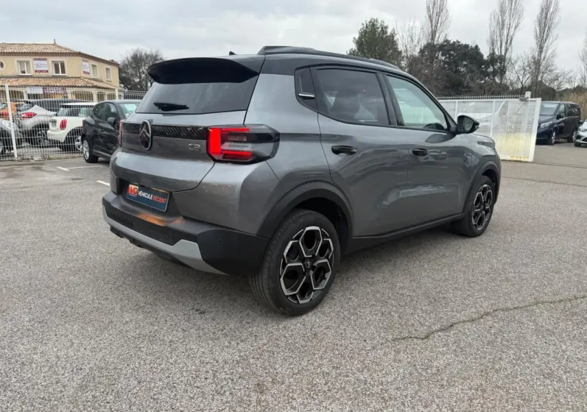 Vue 3/4 arrière droite d'une Citroën C3 gris 2025 avec jantes alliage 17 pouces et barres de toit visibles.