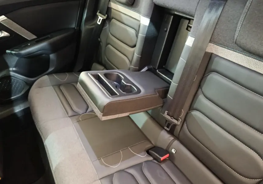 Vue intérieure des sièges arrière gris foncé de la Citroën C4 avec accoudoir central relevé et porte-gobelets intégré.