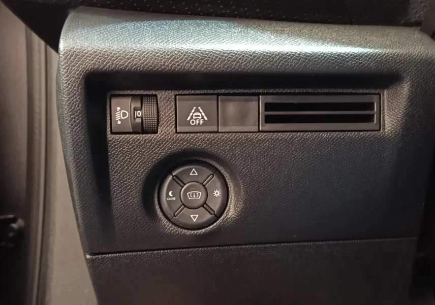 Gros plan sur les commandes de réglage des phares et de l'aide au maintien de voie, tableau de bord noir intérieur Citroën C4.