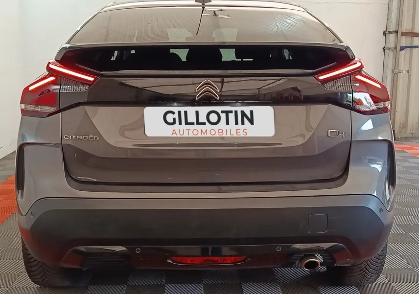 Vue arrière d'une Citroën C4 gris foncé avec feux arrière LED allumés dans un garage.
