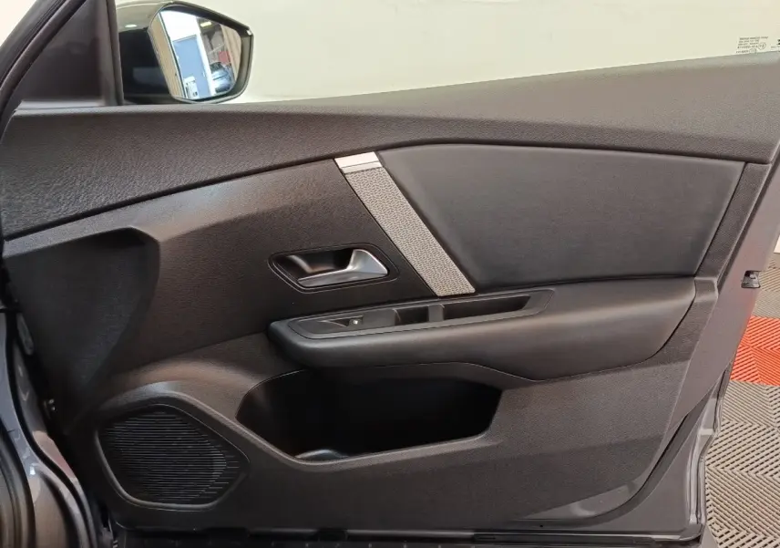 Vue intérieure côté gauche de la porte avant gris foncé de la Citroën C4 2022 avec poignée et haut-parleur intégré.