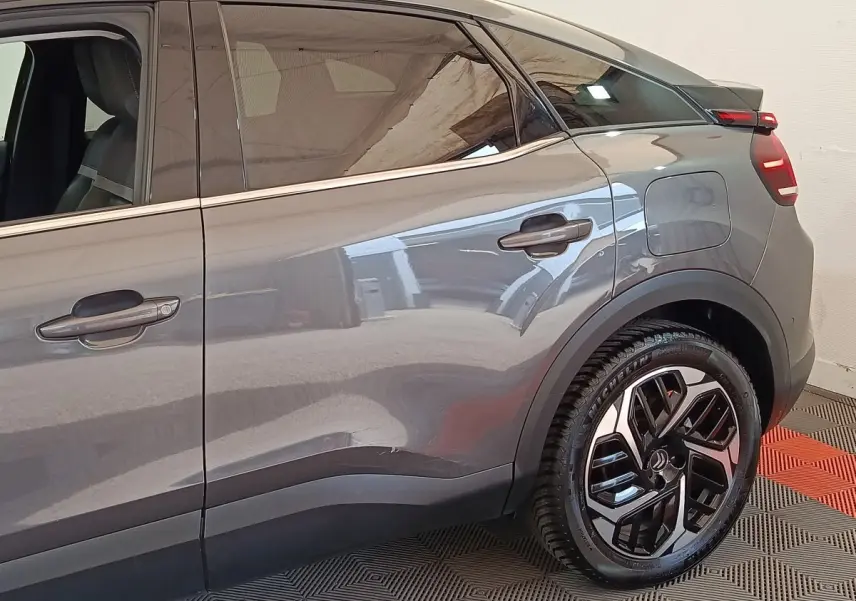 Vue latérale droite sur la partie arrière d'une Citroën C4 gris foncé avec jante alliage et porte de coffre visible.