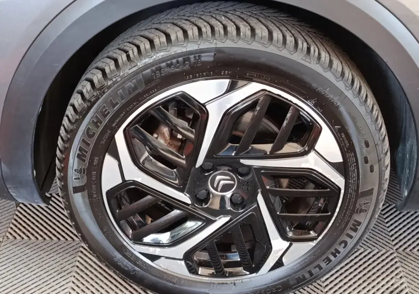 Gros plan sur la roue avant droite avec jante alliage bicolore noire et argentée du Citroën C4 gris foncé.