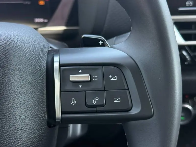 Gros plan sur les commandes au volant à gauche de la Citroën C4 2025, boutons de volume et appels visibles.