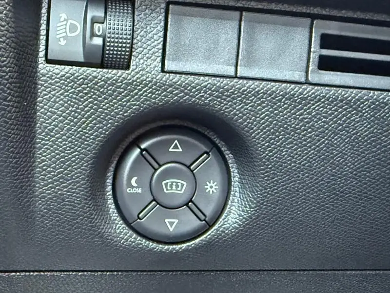 Gros plan sur le bouton de réglage des rétroviseurs dans l’habitacle noir texturé d’une Citroën C4 Gris Mercury 2025.