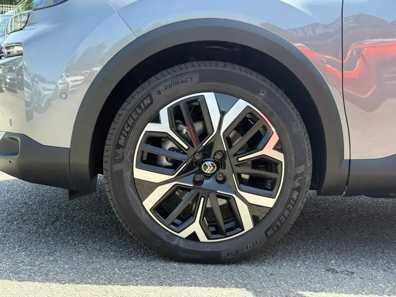 Gros plan sur la roue avant gauche d'une Citroën C4 gris Mercury avec jante alliage noire et argentée.