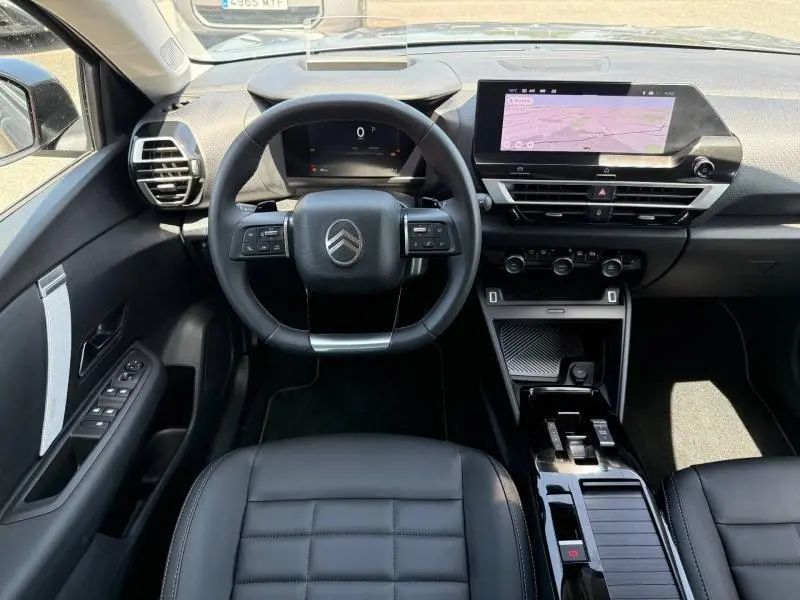 Vue intérieure avant du poste de conduite de la Citroën C4 2025, avec volant multifonction et écran tactile GPS.