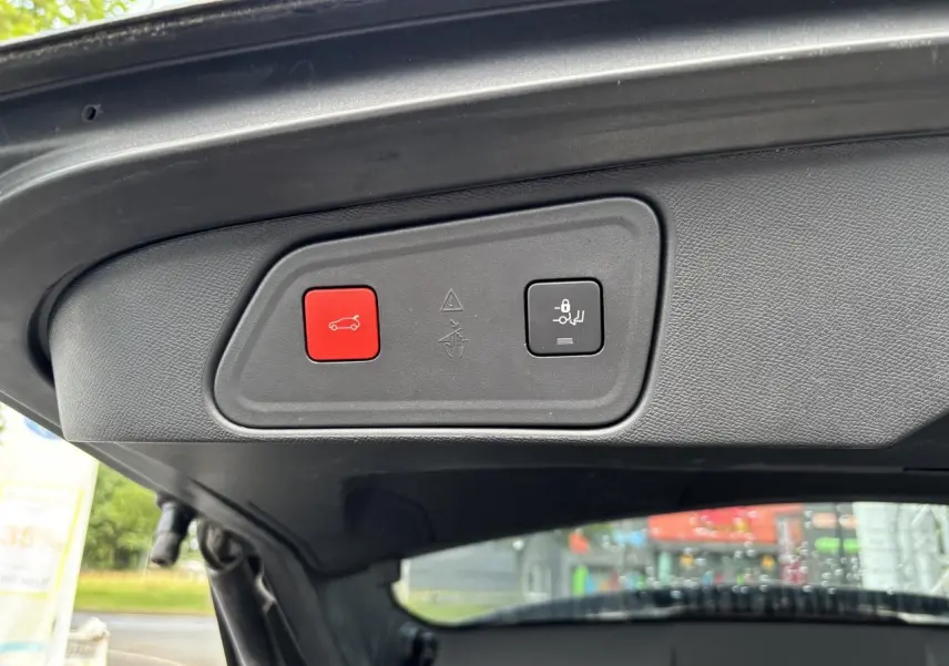 Gros plan sur le panneau de commande du hayon motorisé du Peugeot 3008 noir, avec bouton rouge d'ouverture et bouton de verrouillage.