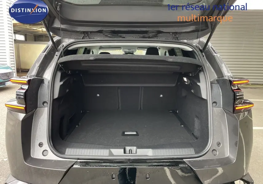 Coffre ouvert vu de l’arrière d’un Citroën C5 Aircross Hybrid gris platinium métal, feux arrière allumés.