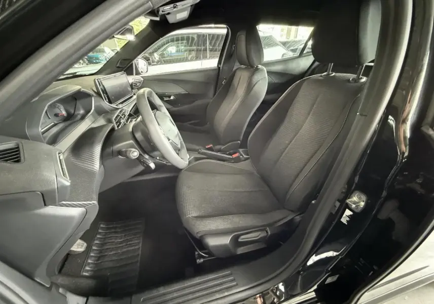 Intérieur noir perla du Peugeot 2008 2025, vue côté conducteur avec sièges tissu et tableau de bord moderne.