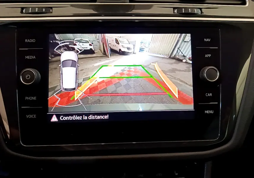 Écran tactile du tableau de bord montrant la caméra de recul avec alertes de distance du Volkswagen Tiguan gris clair.