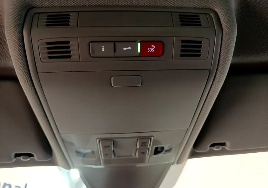 Vue en contre-plongée du panneau de commande intérieur gris du toit d'un Volkswagen Tiguan 2.0 TDI 150 DSG7 Life Business avec bouton SOS rouge allumé.