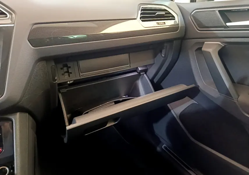Intérieur du Volkswagen Tiguan 2.0 TDI 2021 montrant la boîte à gants ouverte côté passager, finition gris foncé.