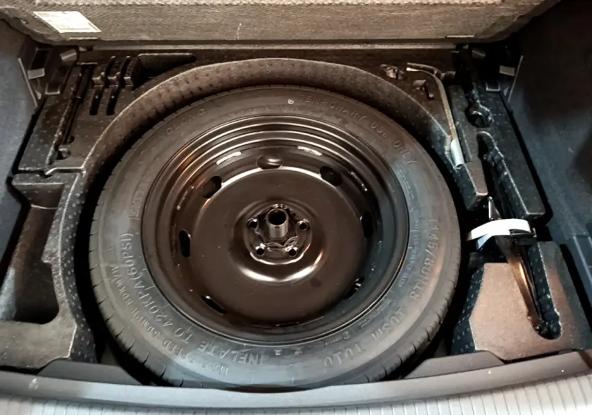 Gros plan sur la roue de secours noire dans le coffre du Volkswagen Tiguan gris clair 2021.