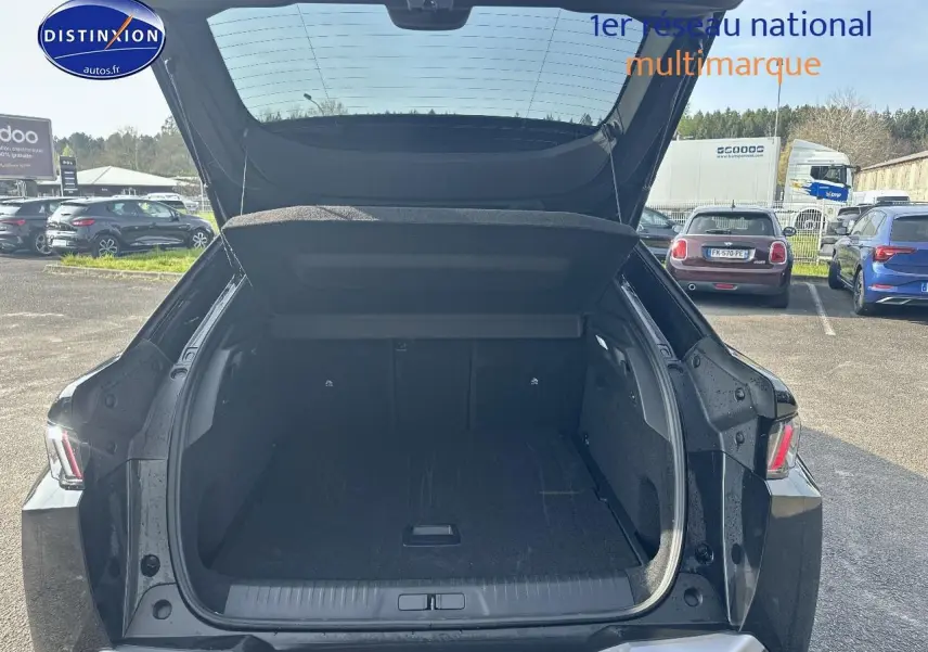 Coffre ouvert d’un Peugeot 3008 noir perla nera, vue arrière en extérieur sur parking ensoleillé.