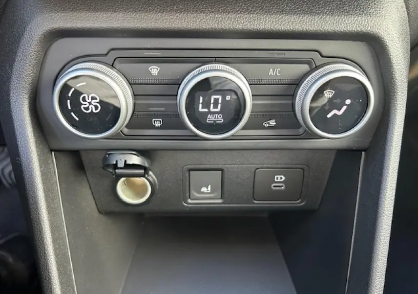 Gros plan sur la console centrale noire du Dacia Sandero Stepway 2025, montrant les commandes de climatisation automatique.