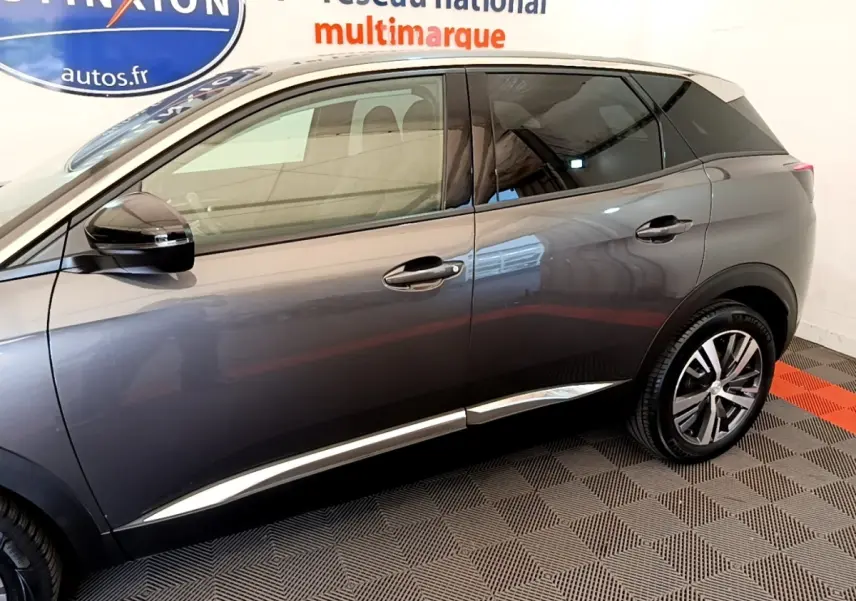 Vue latérale droite d'un Peugeot 3008 gris foncé 2022, avec jantes alliage et vitres teintées, en intérieur showroom.