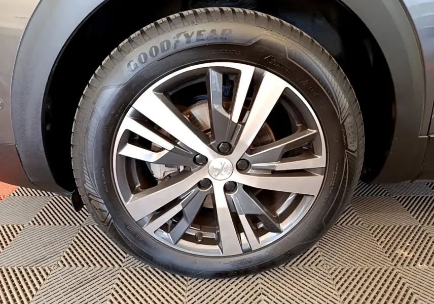 Gros plan sur la roue avant gauche du Peugeot 3008 gris foncé, avec jante alliage et pneu Goodyear visible.