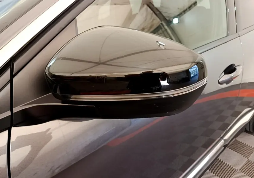 Gros plan sur le rétroviseur côté gauche d’un Peugeot 3008 gris foncé, avec clignotant intégré.