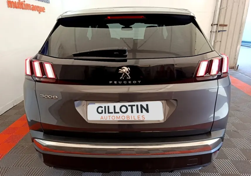 Vue arrière d’un Peugeot 3008 gris foncé avec feux arrière allumés et logo lion visible.