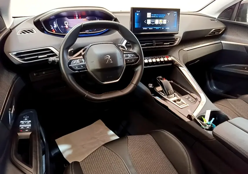 Vue intérieure du poste de conduite du Peugeot 3008 gris foncé, avec volant compact, écran tactile central et tableau de bord digital.