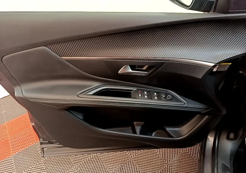 Vue intérieure côté gauche de la porte avant d'un Peugeot 3008 gris foncé, avec commandes de vitres et rétroviseurs.