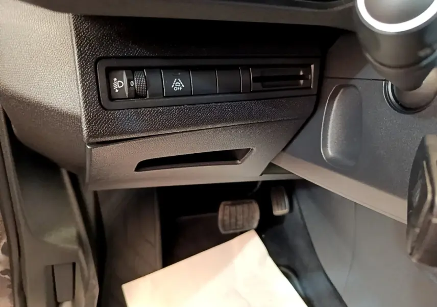 Vue intérieure côté conducteur du Peugeot 3008 gris foncé, avec commandes d’éclairage et pédales visibles.