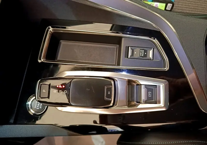 Vue rapprochée de la console centrale noire brillante du Peugeot 3008 2022 avec levier de vitesses automatique et bouton start/stop.