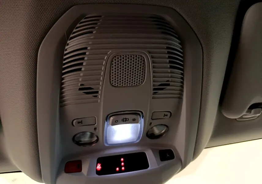 Vue en gros plan du plafonnier intérieur gris clair avec éclairage et commandes dans un Peugeot 3008 gris foncé.