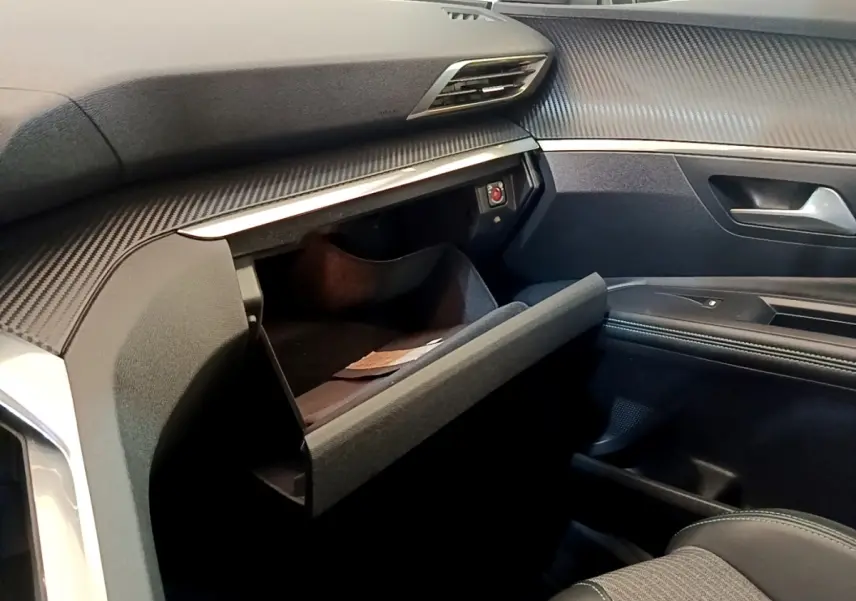 Vue intérieure côté passager du Peugeot 3008 2022 gris foncé, avec boîte à gants ouverte et tableau de bord texturé.